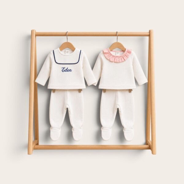 Ensembles de naissance blancs, col marin brodé Eden et collerette rose, sur un portant en bois
